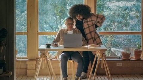 Eine Person hilft einer anderen bei der Bedienung des Computers