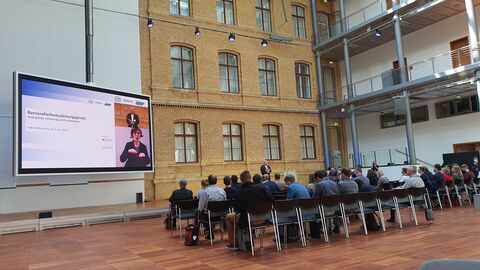 Veranstaltungsort Veranstaltungsort der Konferenz. Links im Bild hängt ein sehr großer Monitor.