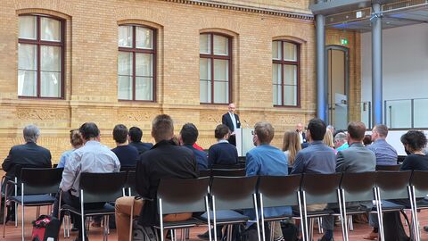 Teilnehmende der Konferenz sitzen in Reihen.