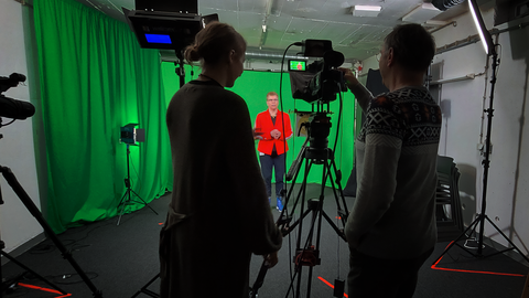 Videoaufnahme vor Greenscreen. Zwei Personen stehen hinter der Kamera. Videoaufnahme vor Greenscreen. Zwei Personen stehen hinter der Kamera.